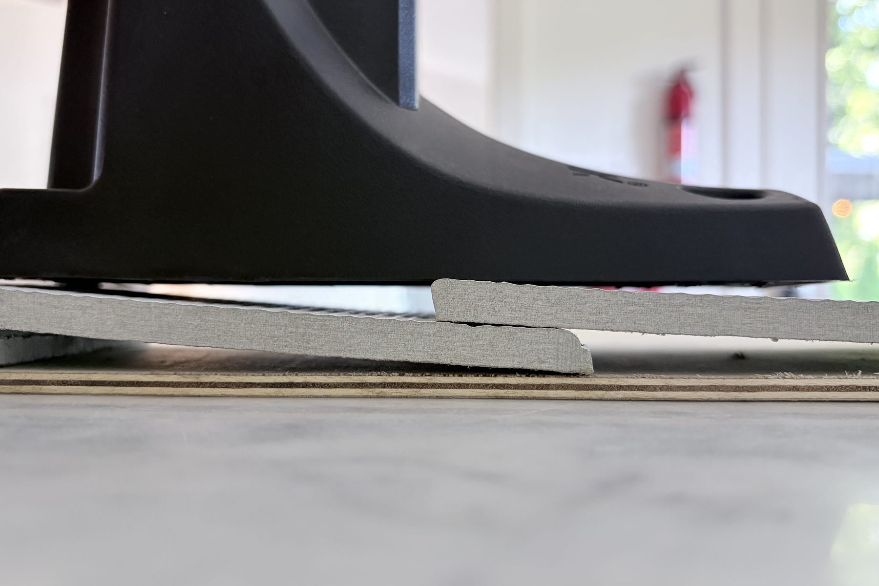 Hoselink bracket laid directly across two overlapping siding courses with a gap under its flat back