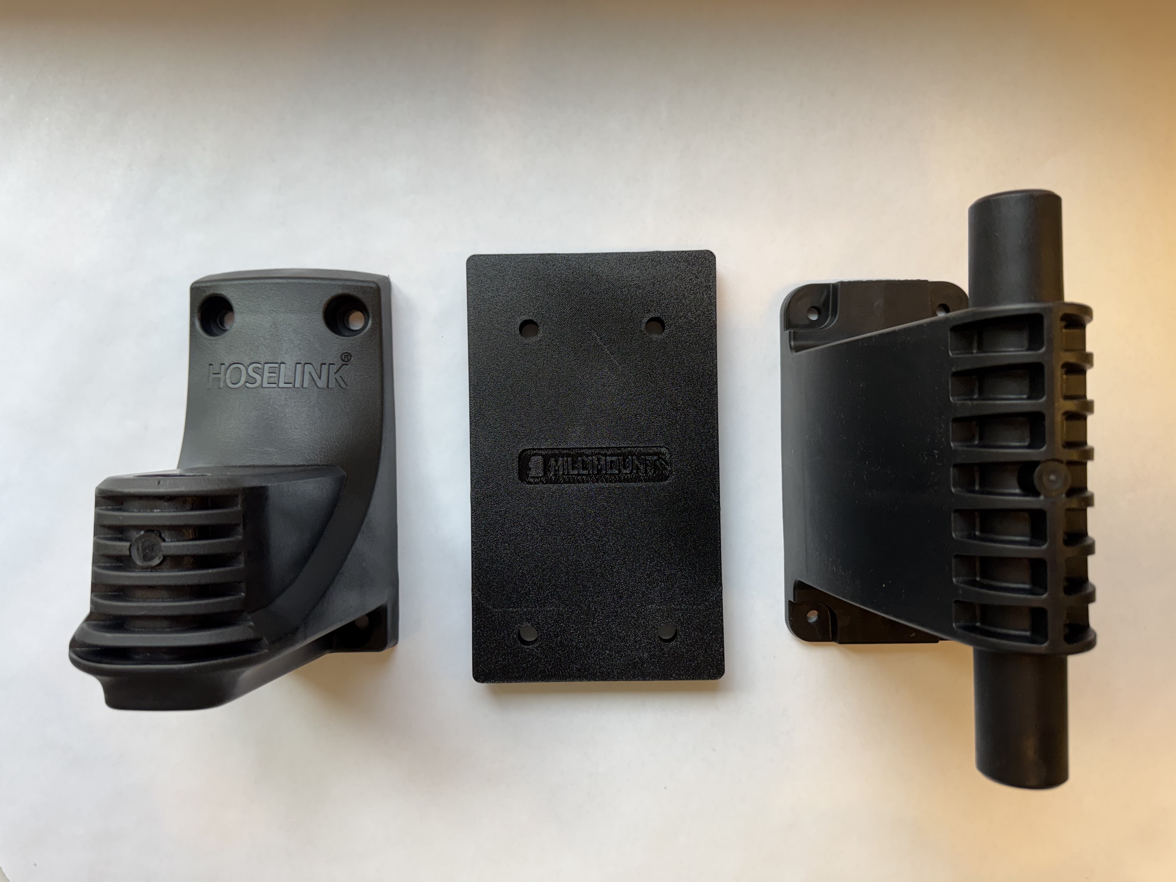 MilliMount bracket shown between both Hoselink Classic and Evolve wall brackets, demonstrating compatibility with both models